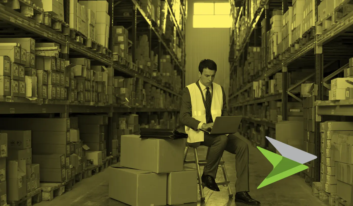 Man in high viz jacket working on laptop in middle of warehouse racks. In a yellow tone.