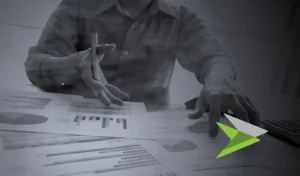 Persons pointing at reports on desk in a black and white