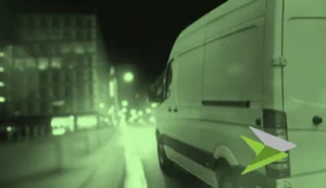 Van on an urban street at night, in a green tone.