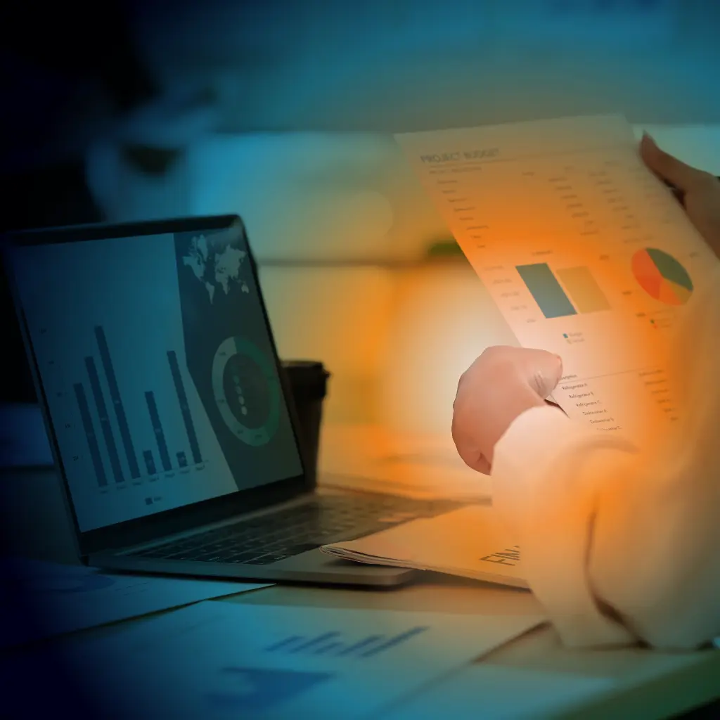 A person reviewing documents in front of laptop screen