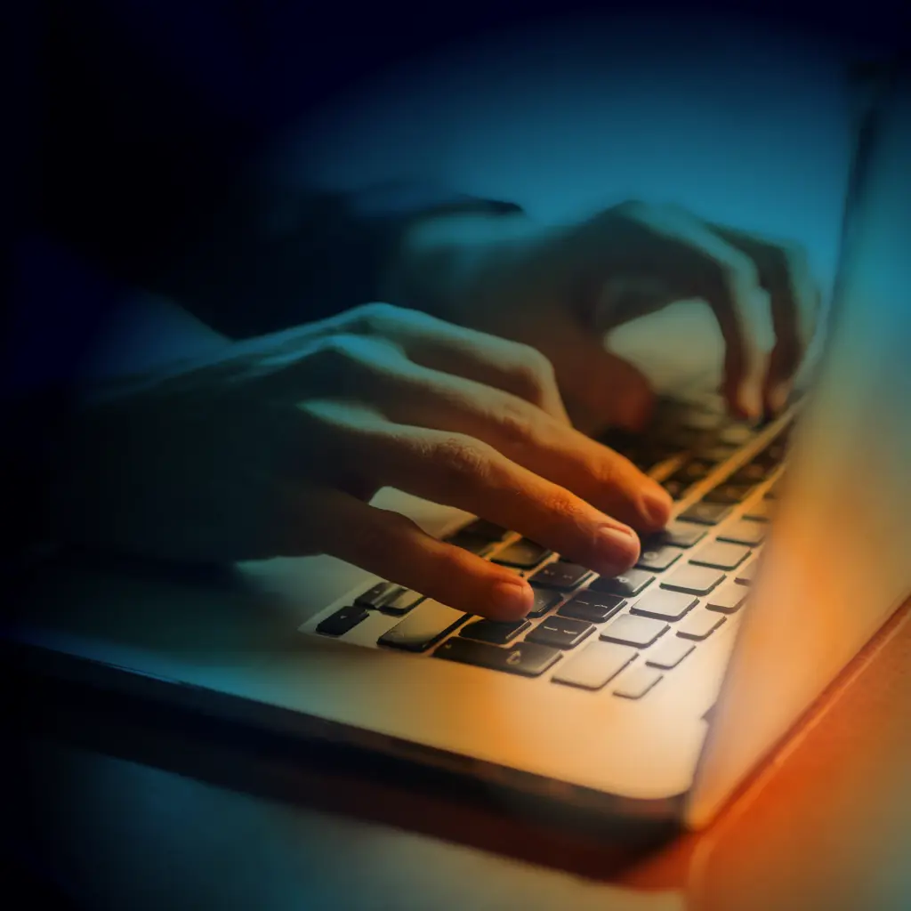 Hands typing on a laptop keyboard