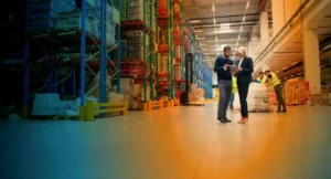 Two people talking in the middle of a warehouse and looking at a clipboard