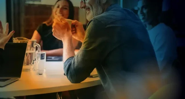 A man drinking coffee whilst talking to collegues