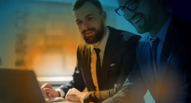 Two people looking at a laptop screen in an office